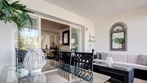 A modern dining area with a glass table, black chairs, and a glass coffee table. - Apartment "La Perla de Marakech 5" with Sea View, Shared Pool & Wi-Fi (Casares)