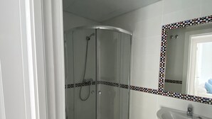 A bathroom with a glass shower enclosure, a sink, and a tiled backsplash.