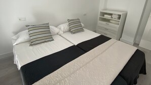 A double bed with a black and white bedspread, a striped pillow, and a bedside table with a white lamp.