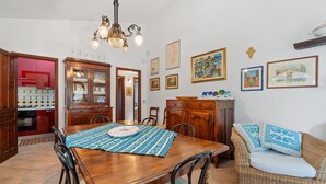 Una zona de menjador amb taula de fusta, cadires, un sofà de fibra i un penjador.