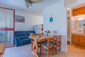 Un espacio habitable compacto con una mesa de comedor, sillas, un sofá, una kitchenette y una puerta que da a un área exterior.