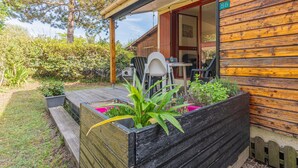 A wooden cabin with a porch, a dining table, and chairs.
