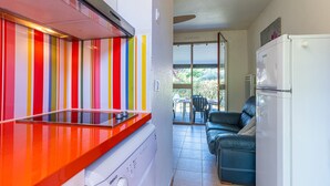 A kitchen with a colorful striped wall, a white Bosch refrigerator, and a blue sofa in the adjacent living area.