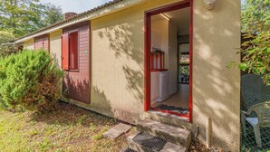 A small building with a red door and a window, a small porch, and a doorbell.