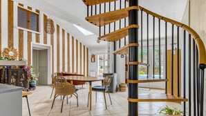 Ein modernes Interieur mit einer Holztreppe, einem Essbereich mit Korbstühlen und einer Küche mit Einbauherd.
