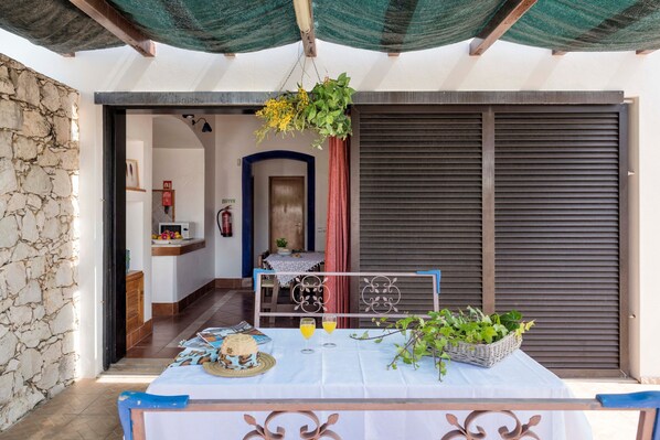 A room with a table set for breakfast, a hanging plant, and a view of the outside.