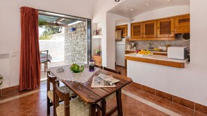 Un espace repas comprenant une table, des chaises et une vue à travers une porte vitrée.