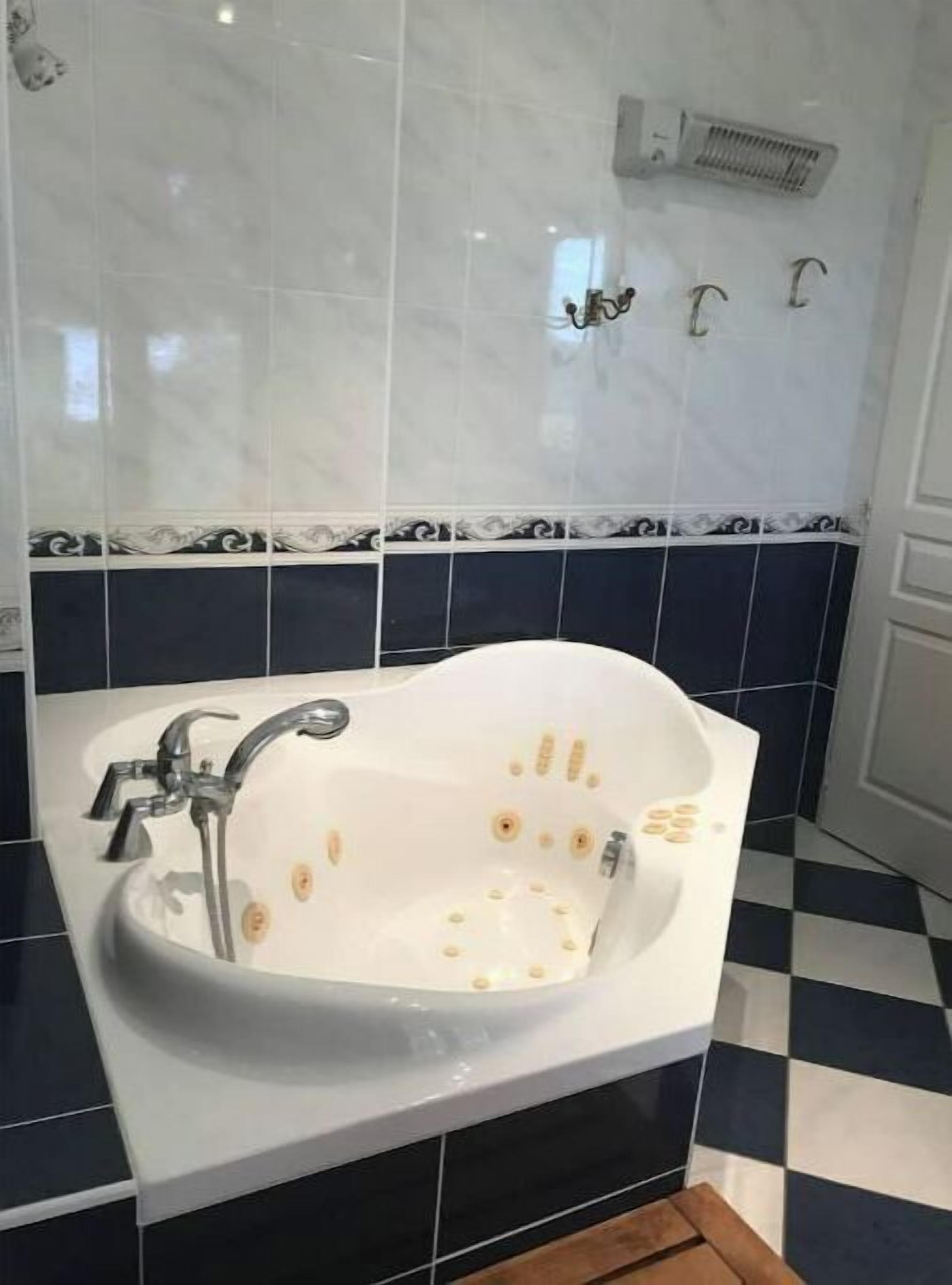 Un baño con una bañera independiente, un calentador de pared y un piso con diseño de cuadros.