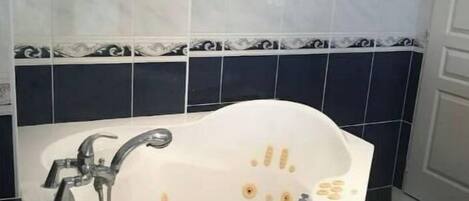 Un baño con una bañera independiente, un calentador de pared y un piso con diseño de cuadros.