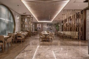 A spacious dining area with marble flooring, modern lighting, and a variety of seating arrangements.