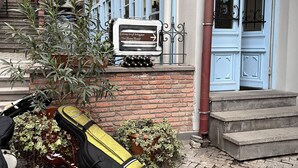 A Tbil Home Hostel sign, a building with blue doors, and luggage on the steps. - TbilHome hostel (Tbilisi)