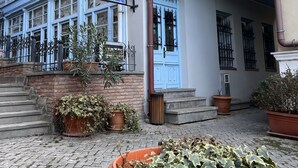A two-story building with a balcony, a blue door, and a sign indicating it is a hostel. - TbilHome hostel (Tbilisi)
