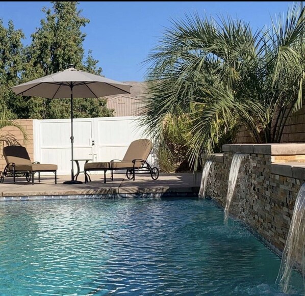 Relax by the serene pool surrounded by lush greenery and a small waterfall.