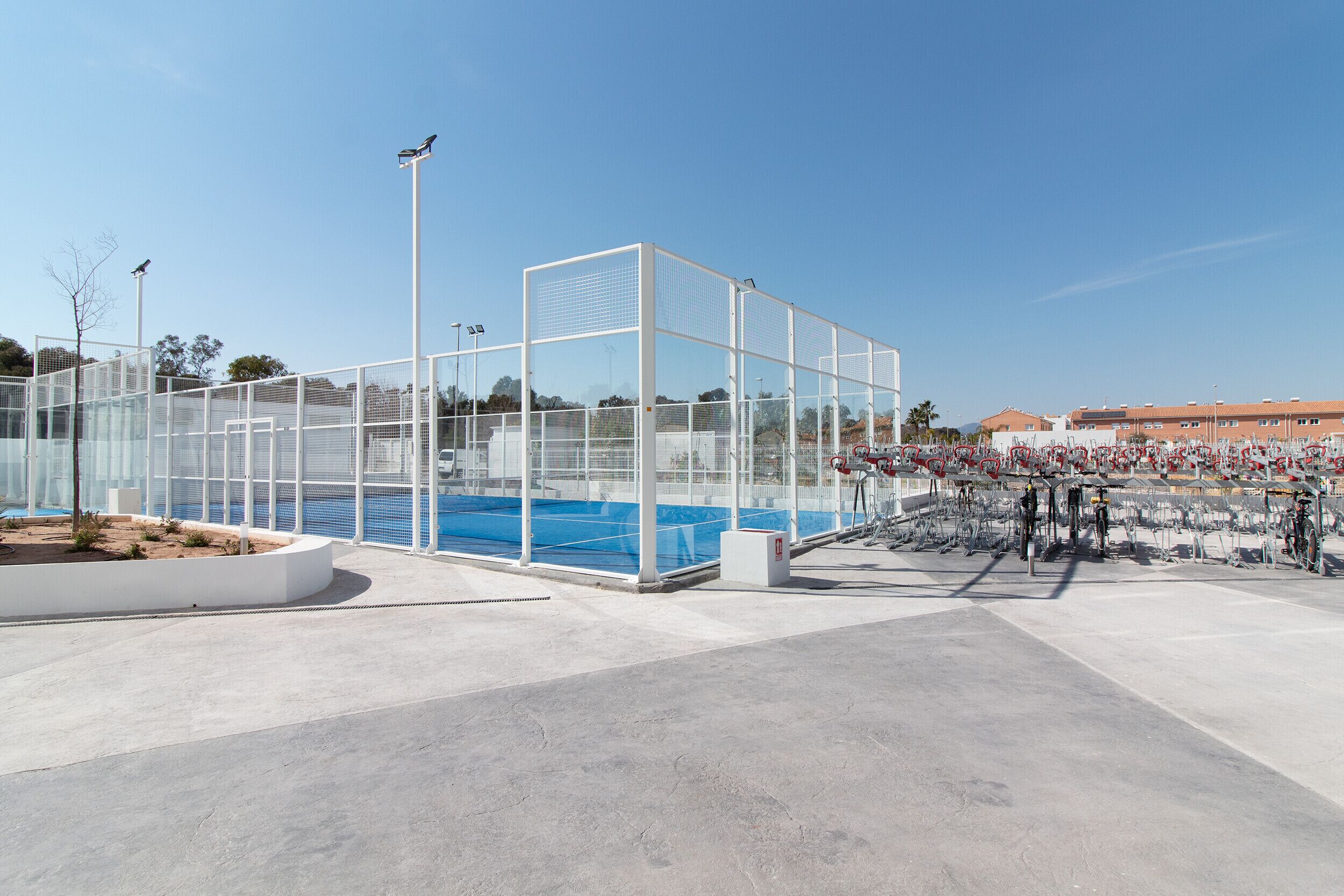 Una instalación deportiva moderna con piscina techada, gradas para espectadores y cielo despejado.