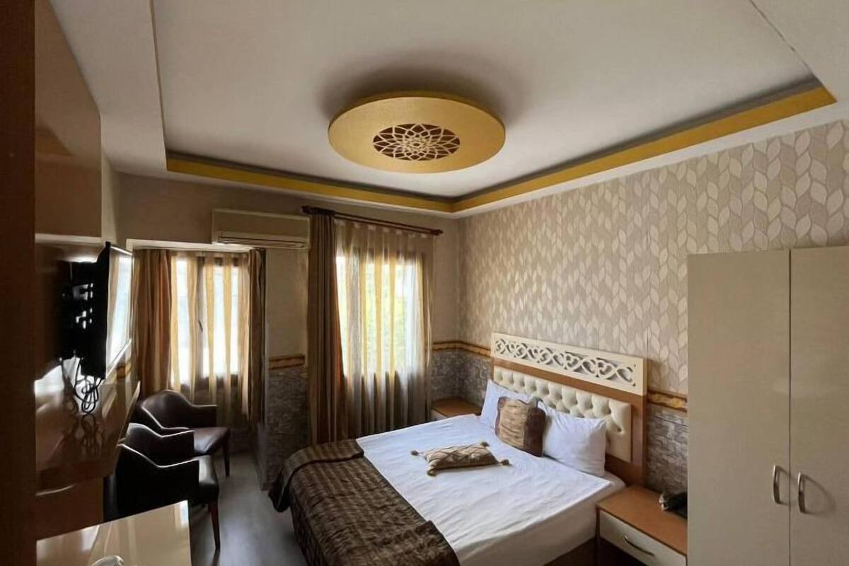 A hotel room with a bed, a desk, a wardrobe, and a television.