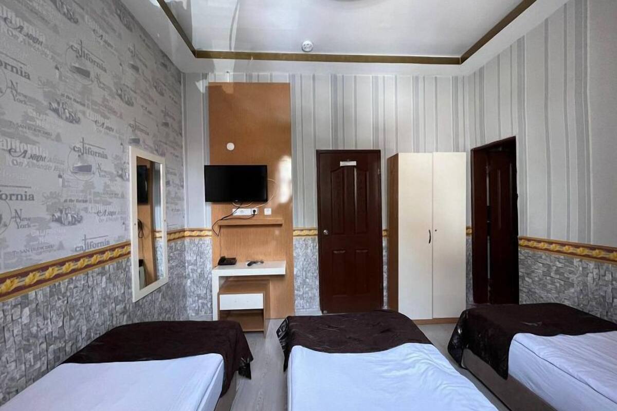 A hotel room with two beds, a TV, a wardrobe, and a mirror.