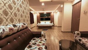 Una habitación de hotel moderna con una cama grande, un sofá, una mesita pequeña y suelo de madera.