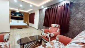 Una habitación de hotel moderna con una cama, un sofá, una mesa de centro y un ventanal con cortinas.