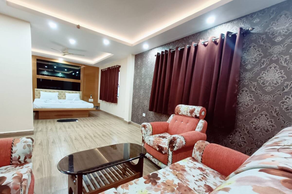 Una habitación de hotel moderna con una cama, un sofá, una mesa de centro y un ventanal con cortinas.