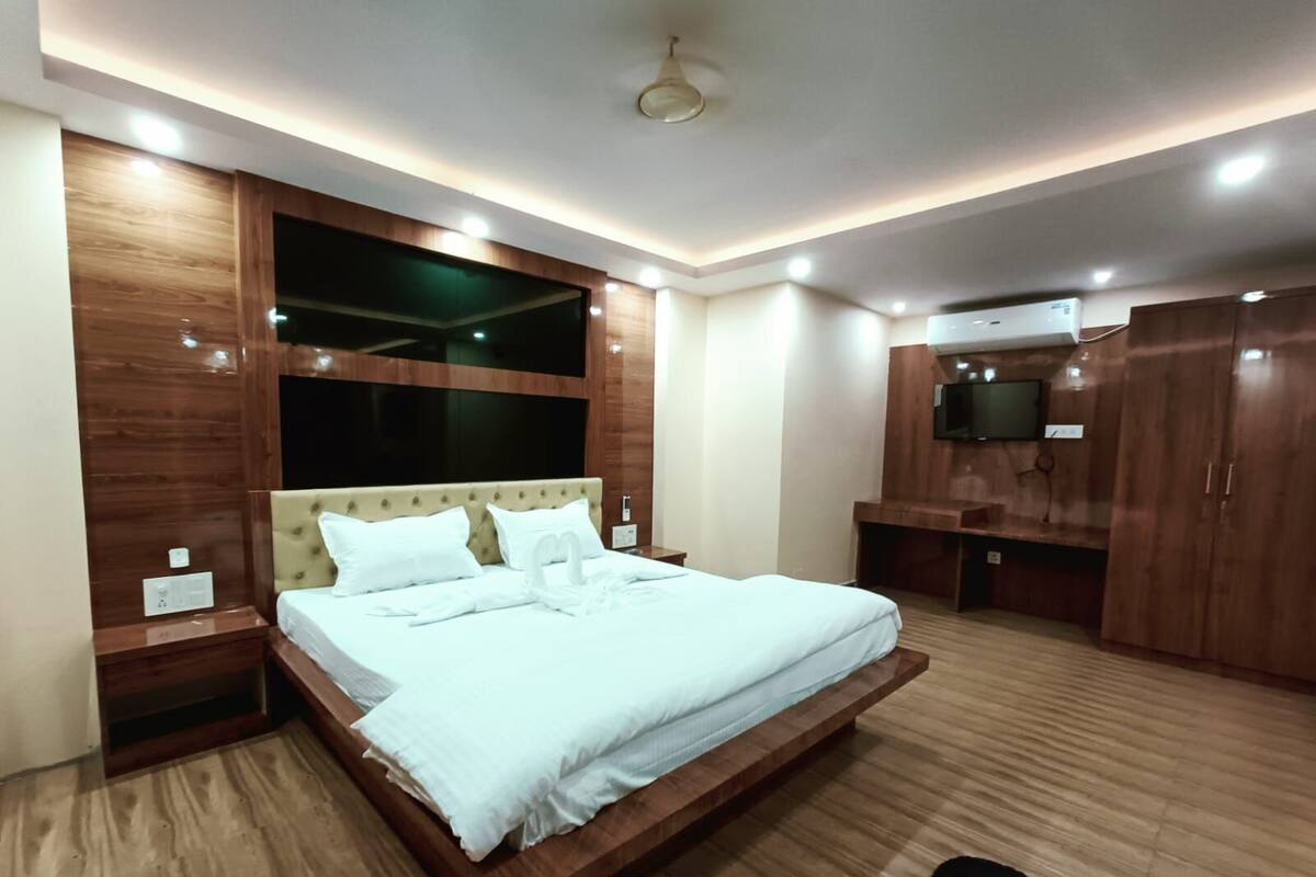Un dormitorio moderno con una cama grande, paneles de madera, un televisor de pantalla plana y armarios empotrados.