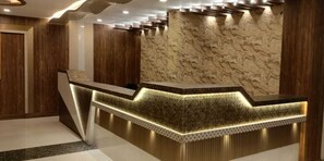 A reception desk with a marble back wall and wooden paneling. - Jyoti International (Asansol)