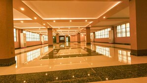 Un espacioso vestíbulo de hotel con piso de mármol pulido, ventanas amplias y un área central abierta.