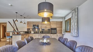 Uma cozinha moderna com armários de madeira, uma ilha central e luminárias pendentes.