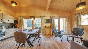 Um interior moderno em madeira com área de jantar, cozinha e espaço para sentar.