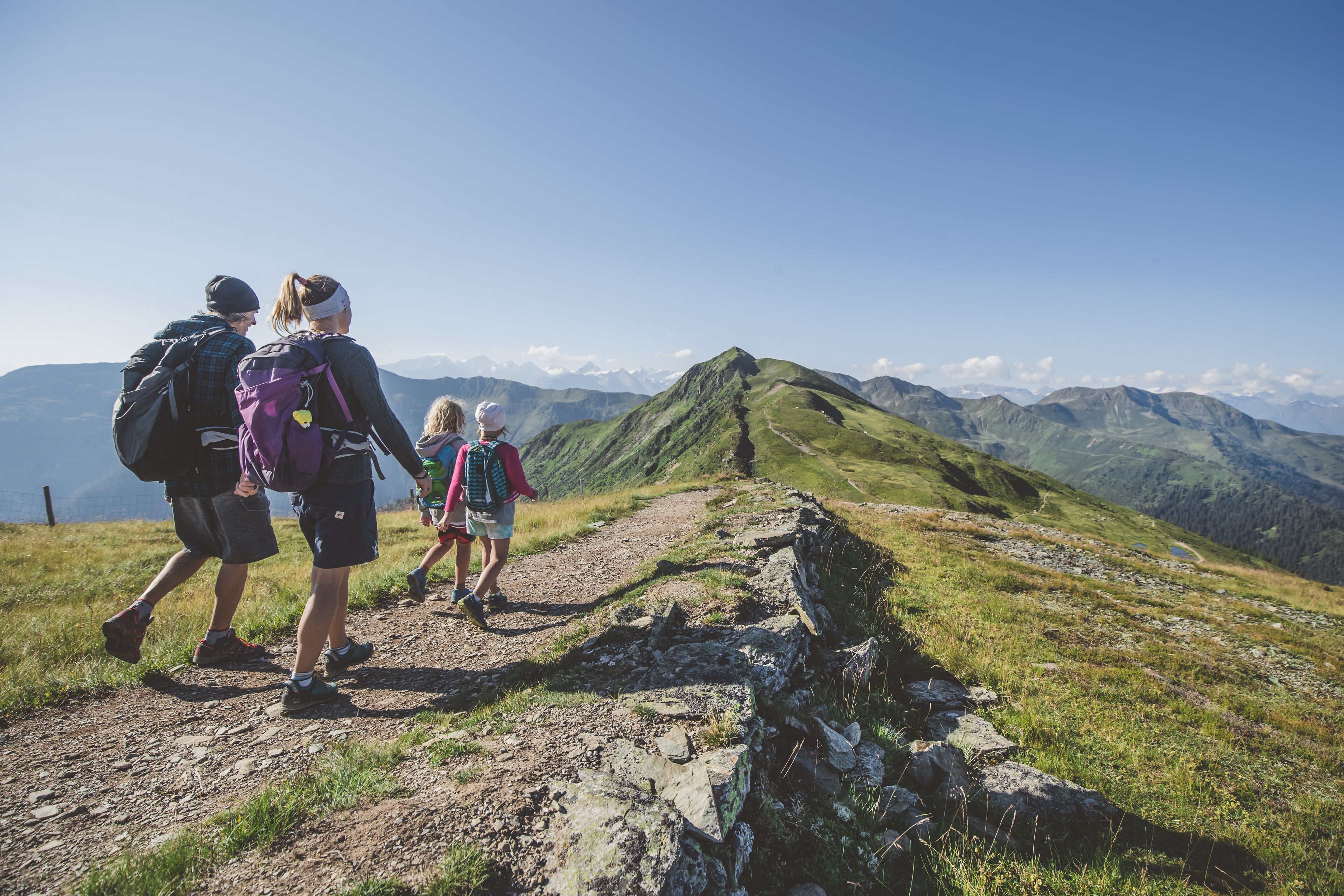 A group of hikers on a rocky trail with a mountainous landscape in the background.