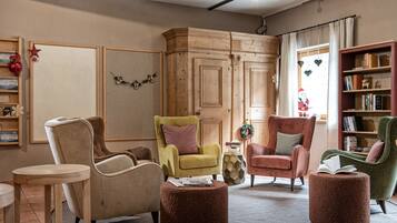Un salón acogedor con un aparador de madera, un sillón verde, un sillón rojo y una estantería.