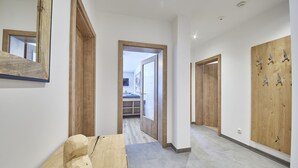 Um corredor com piso de madeira, um banco de madeira e um vão de porta em madeira.