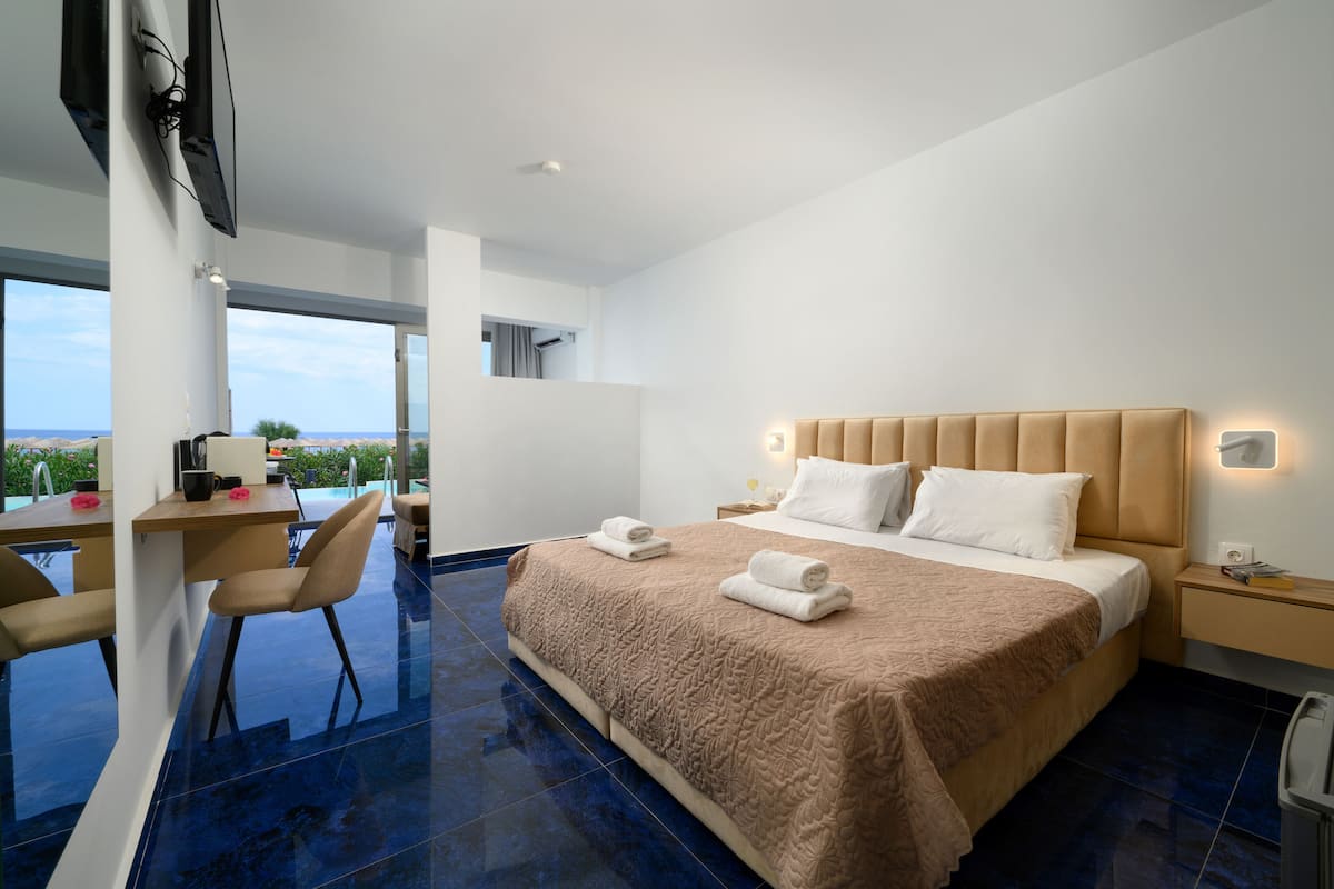 Een moderne hotelkamer met een groot bed, een bureau en uitzicht op zee.