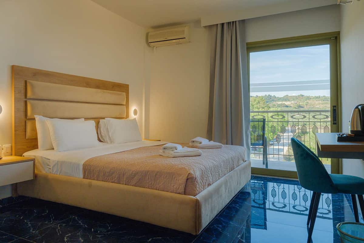 Een hotelkamer met een bed, nachtkastje en uitzicht op de omgeving.