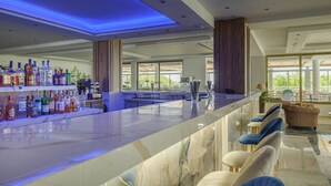 Un moderno bar con mostrador de mármol, diversas botellas de licor y una zona de estar con sillones cómodos.