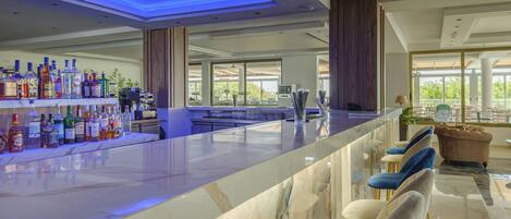 A modern bar area with a marble countertop, a variety of liquor bottles, and a seating area with plush chairs.