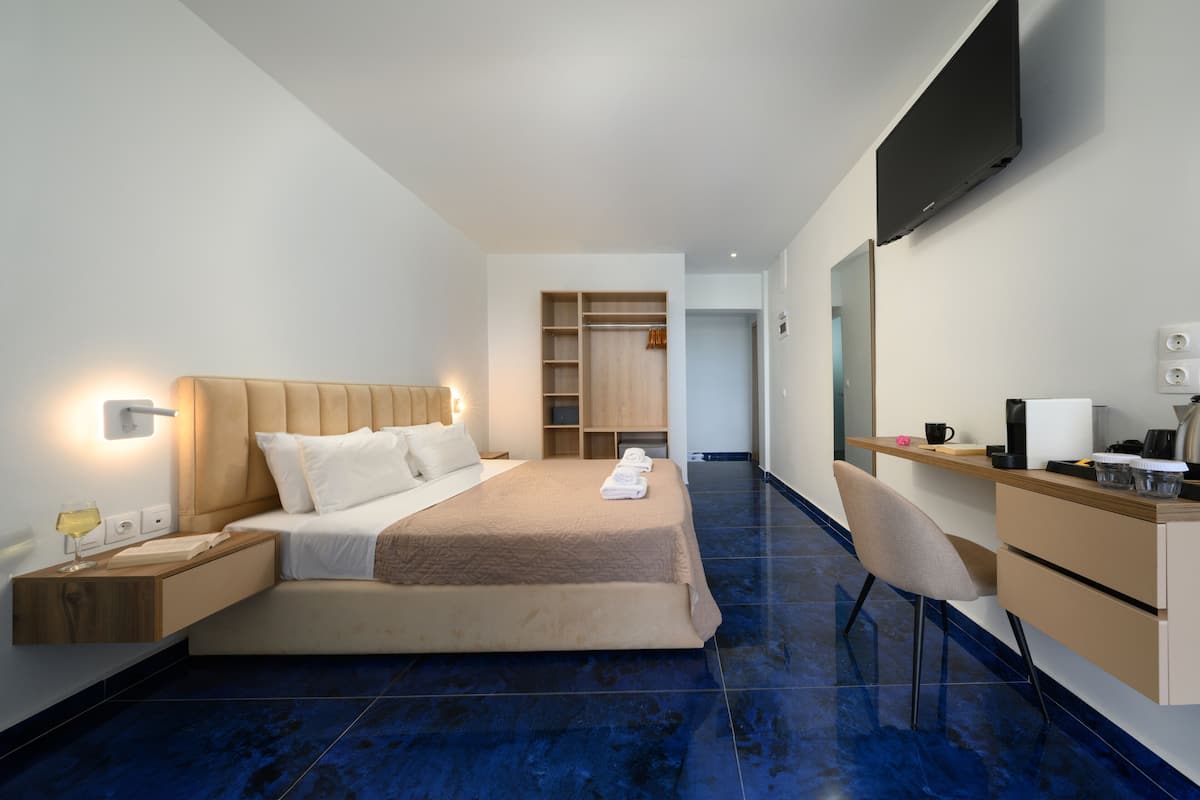 Een moderne hotelkamer met een bed, nachtkastje, bureau, stoel en een kledingkast.