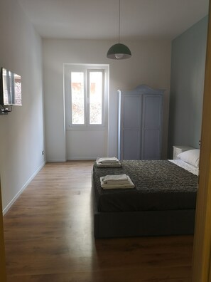 A bedroom with a bed, a wardrobe, a television, and a window. - A stone's throw from the subway (Roma)