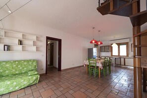 A spacious living area with a sofa, dining table, chairs, and a red pendant light.