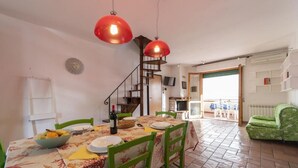 A dining area with a table set for four, a staircase, and a view of the outside.