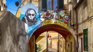Un estrecho callejón con un mural y un arco.