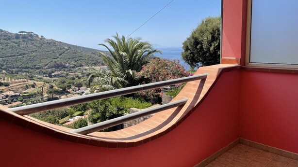 Un balcón con barandilla curva que da a un paisaje pintoresco.