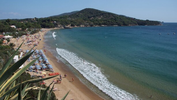 A beach with umbrellas, a sandy shore, and a hill in the background. - Vlletta Grazia 2 apartment (Capoliveri)