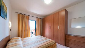 A bedroom with a bed, wooden wardrobe, and a TV. - Vlletta Grazia 2 apartment (Capoliveri)