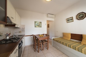 A compact kitchen with a dining table, a sofa, and a stove.