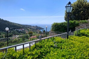 Un balcone con ringhiera, un lampione e vista sul mare e sulle colline.