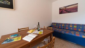 A dining area with a wooden table, chairs, a sofa, and a painting on the wall.