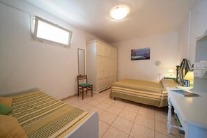 Un dormitorio con dos camas, un armario, una silla, un escritorio y un cuadro en la pared.
