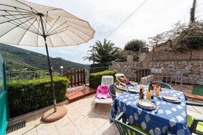 An outdoor dining area with a table set for two, a large umbrella, and a scenic mountain view.