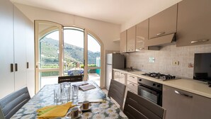 A modern kitchen with a dining area, large windows, and a view of the outdoors.