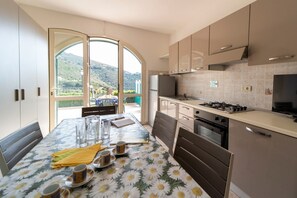 A modern kitchen with a dining area, large windows, and a view of the outdoors.